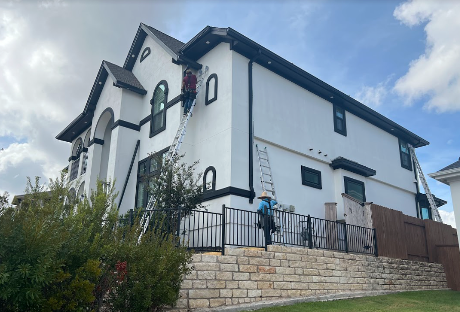 2 men cleaning gutters on a tall home in Austin Texas