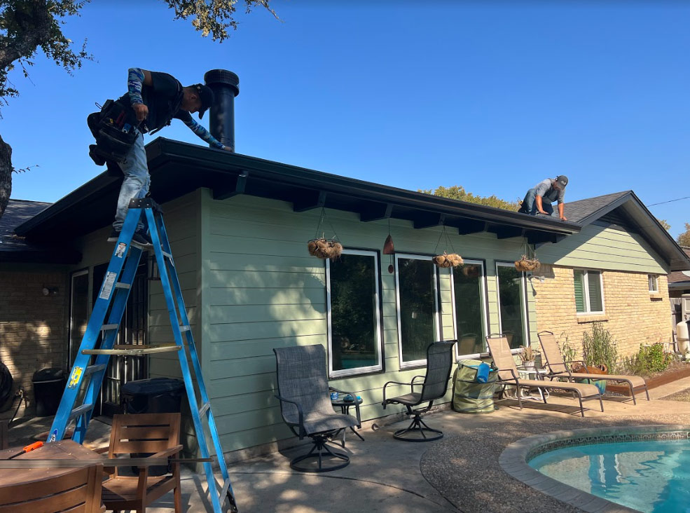 2 men on a roof, one with a ladder cleaning gutters on a house in Austin Texas