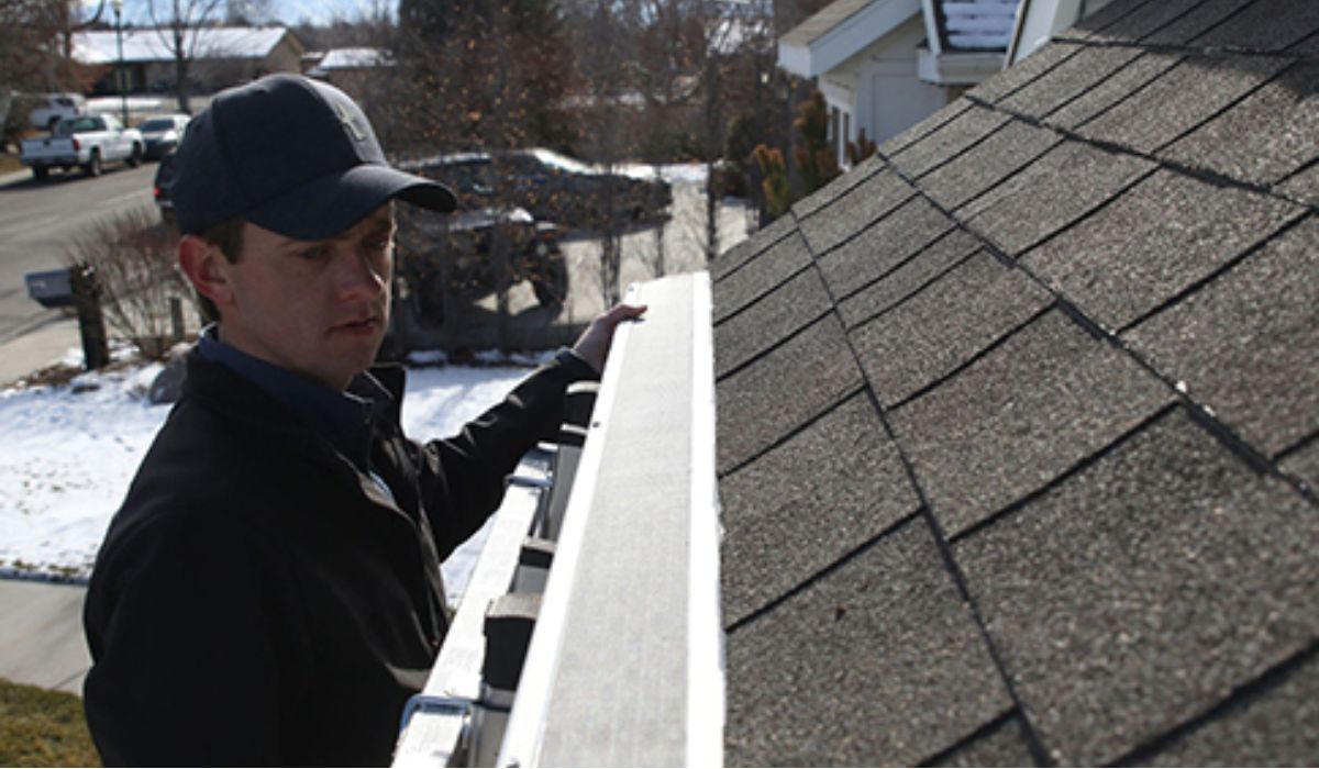 a gutter professional inspecting the gutter on the roof