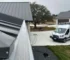 Close-up of gutter guards installation on a modern home in Austin, showcasing the new seamless gutters and a service van in the driveway, illustrating professional gutter services.